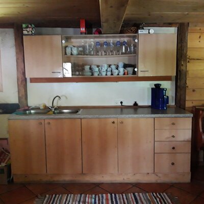 Equipped kitchen area in the farmhouse with a double sink, wooden cabinets, and a coffee maker.