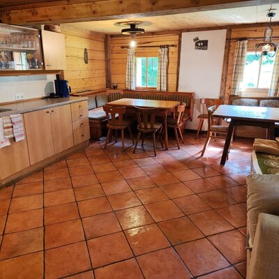 An inviting dining and living area in the bed and breakfast, featuring rustic wooden paneling, warm terracotta tiling, and cozy seating.