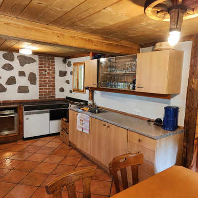 The bed and breakfast's rustic kitchen features cozy wooden cabinetry, a traditional tiled floor, and charming stone accent walls.