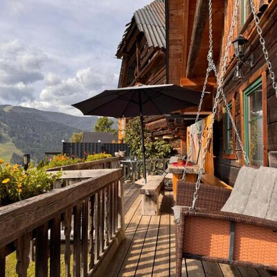 The Ottls Hütte inviting wooden terrace, featuring a cozy hanging swing chair and scenic mountain views.