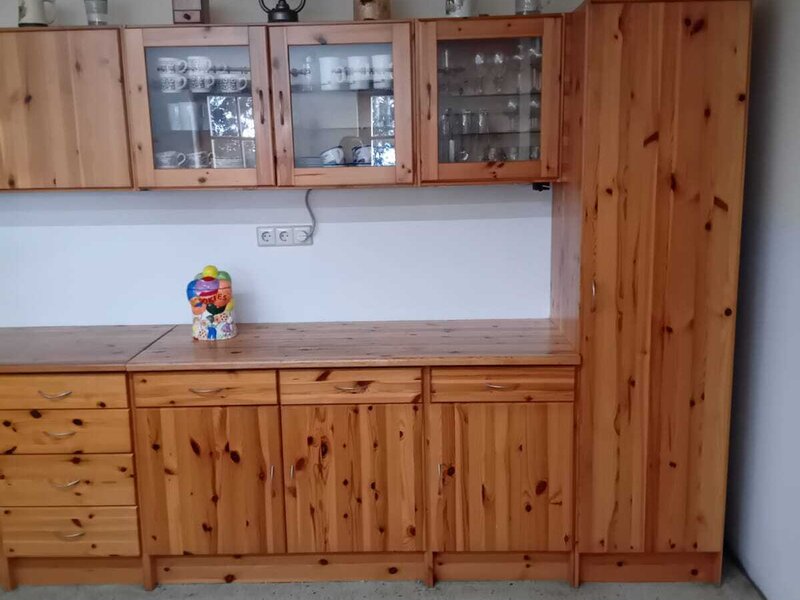 The farmhouse kitchen features wooden cabinets, including glass-fronted units displaying dishes and glasses.