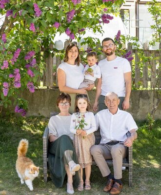 The farmhouse family in the garden with a lilac bush and a cat.