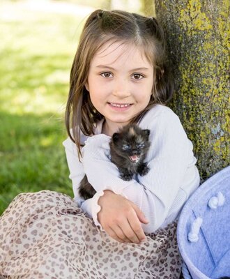 A girl holding a kitten at the farmhouse.