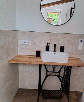 A stylish bathroom in the alpine cabin featuring a modern vessel sink set atop a charming vintage sewing machine base.