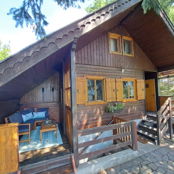 The charming wooden hut featuring a cozy, covered terrace with comfortable outdoor seating.