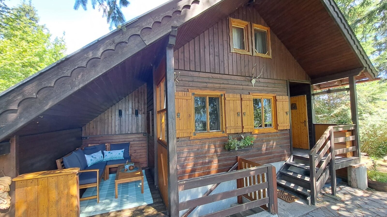 The charming wooden hut featuring a cozy, covered terrace with comfortable outdoor seating.
