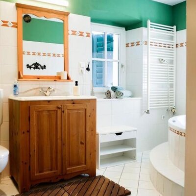 Bathroom in the farmhouse featuring a wooden vanity with a mirror, a window, a bathtub, and a wall-mounted towel heater.