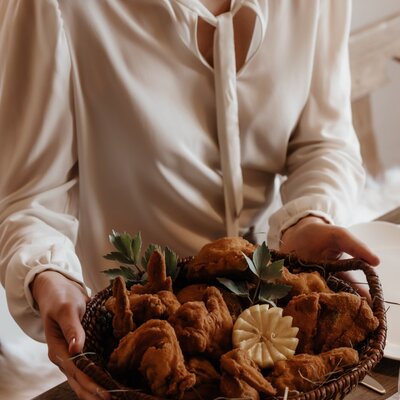 A basket of golden-brown fried poultry, garnished with herbs and a carved lemon, presented on a wooden table at the Farm House.