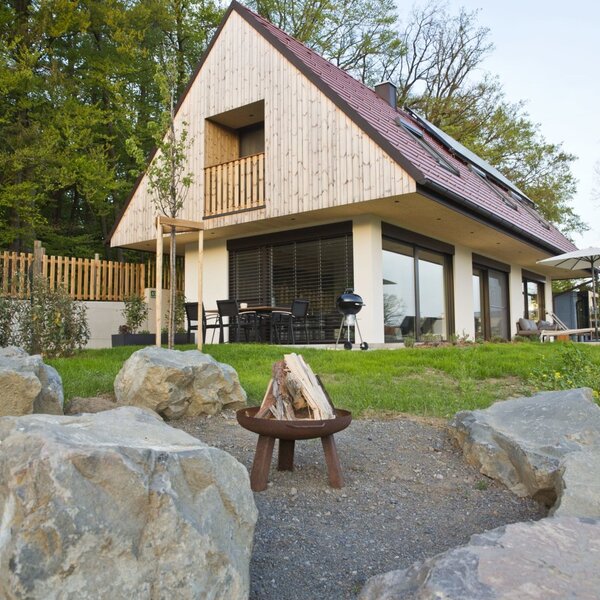 The Farm House features a modern design with wood siding, offering an outdoor dining area with a grill, a hot tub, a fire pit, and a private balcony.