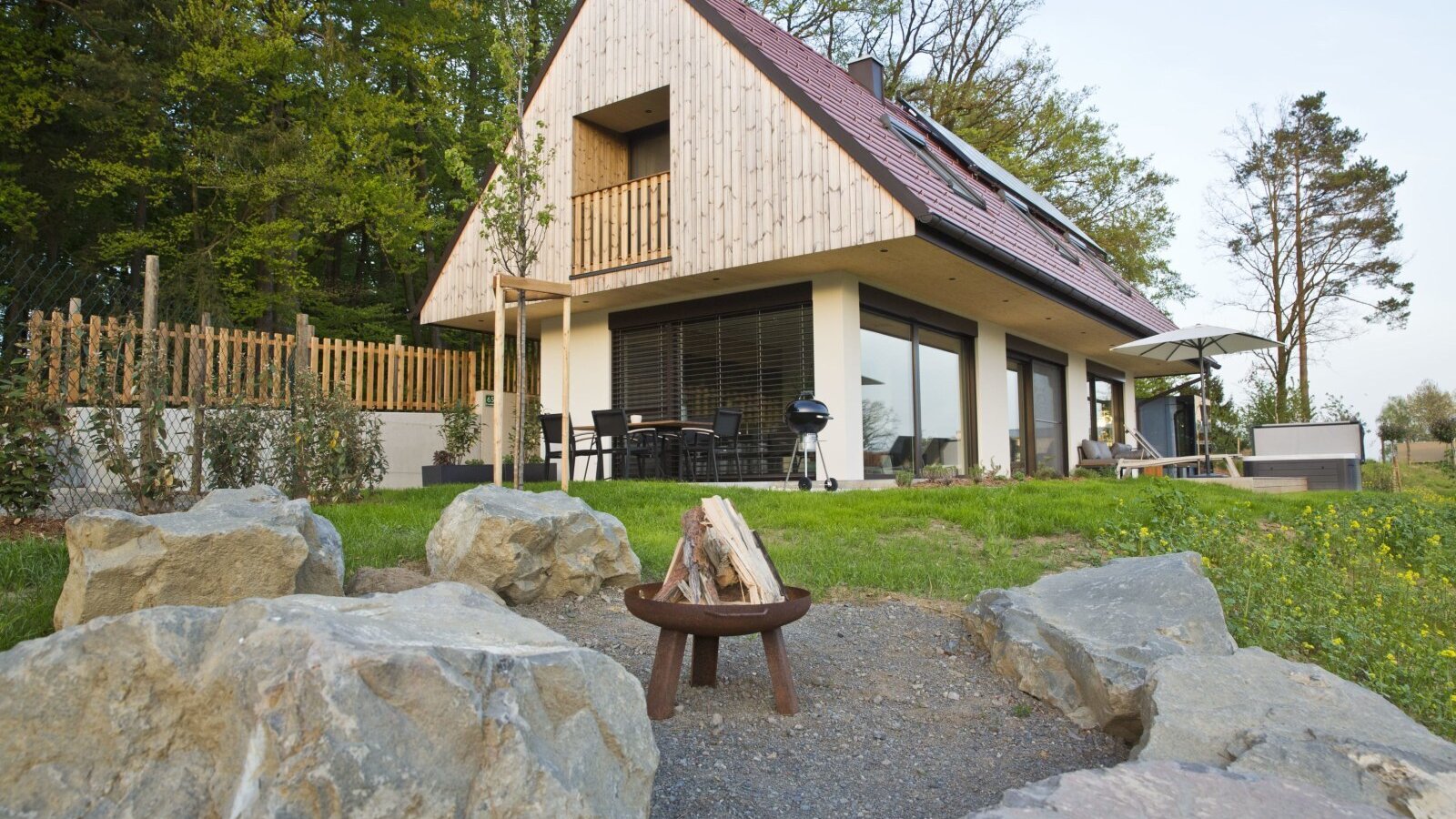 The Farm House features a modern design with wood siding, offering an outdoor dining area with a grill, a hot tub, a fire pit, and a private balcony.