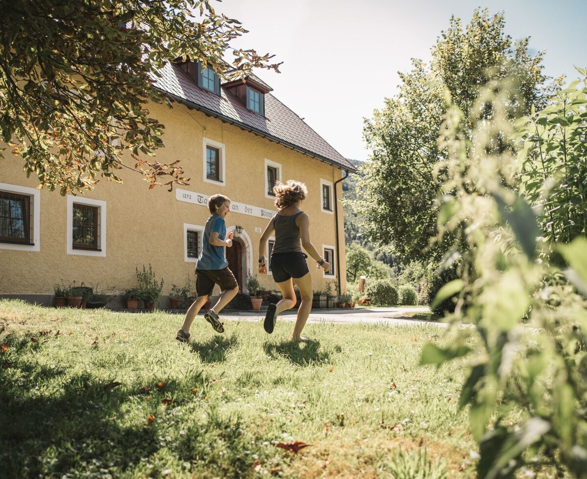 The farm house features a spacious lawn area in front of its yellow exterior, suitable for outdoor activities.