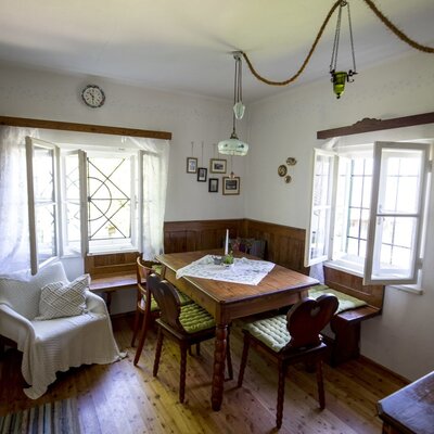 The originally furnished dining area in the hut features a wooden table, a corner bench, and chairs.