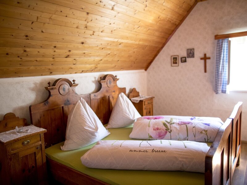 Room 4 with sloped ceiling, rustic double bed, bedside tables, and wood-paneled ceiling