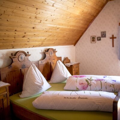 Room 4 with sloped ceiling, rustic double bed, bedside tables, and wood-paneled ceiling