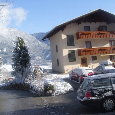 The exterior of the Farm House in winter, featuring multiple balconies and views of the snowy mountains.