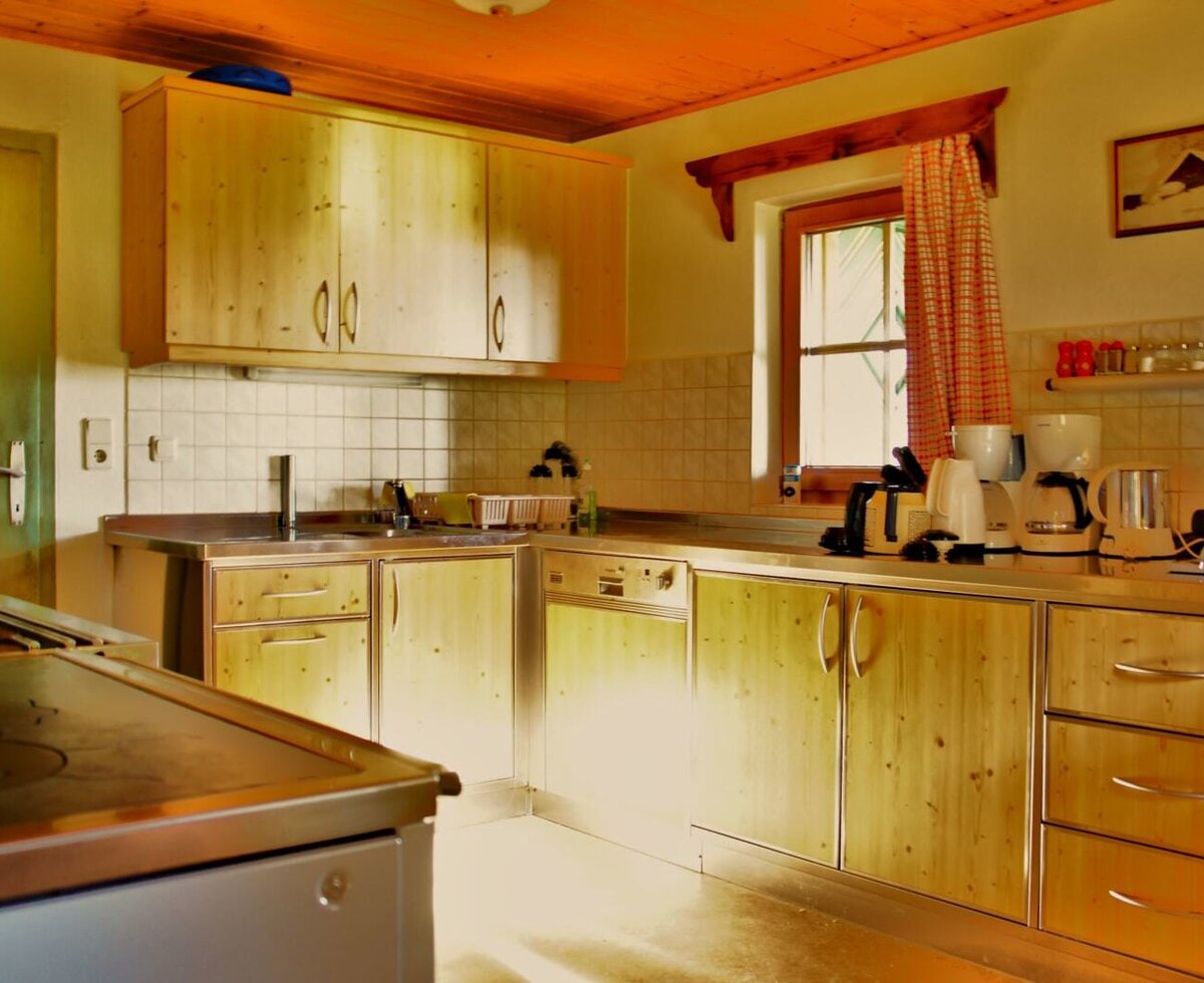 The farmhouse kitchen features wooden cabinets, stainless steel countertops, a large stove, a sink, and small appliances including a kettle and a coffee machine.