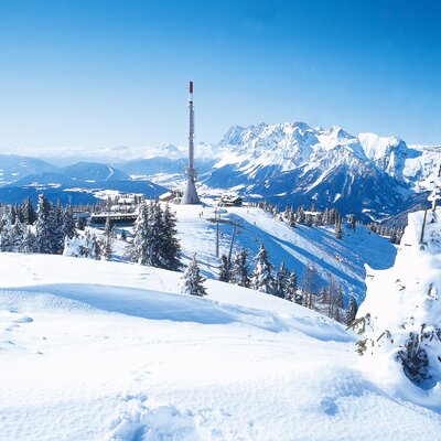 Panoramic view of the snow-covered mountains, ski slopes, and a communication tower surrounding the farmhouse.