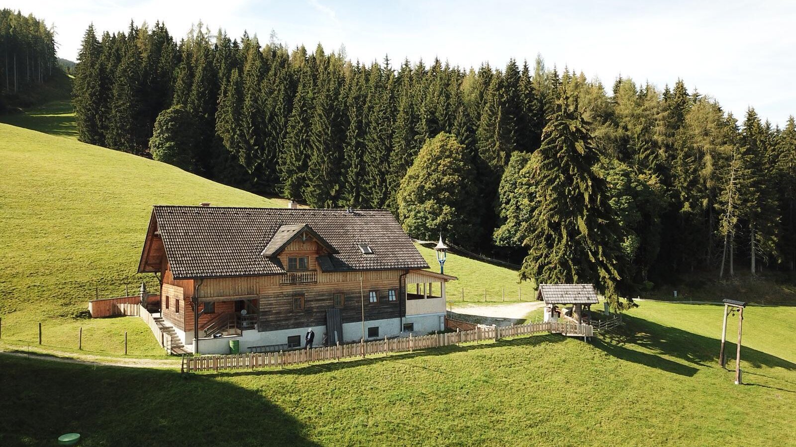 Our mountain cabin, a wooden building nestled on a grassy hillside with a forest backdrop.