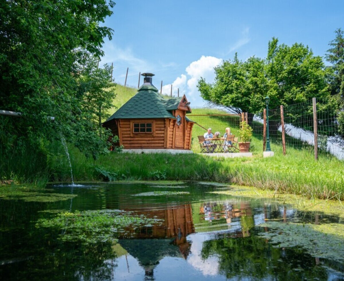 The holiday home's idyllic garden featuring a cozy barbecue hut and a tranquil garden pond.