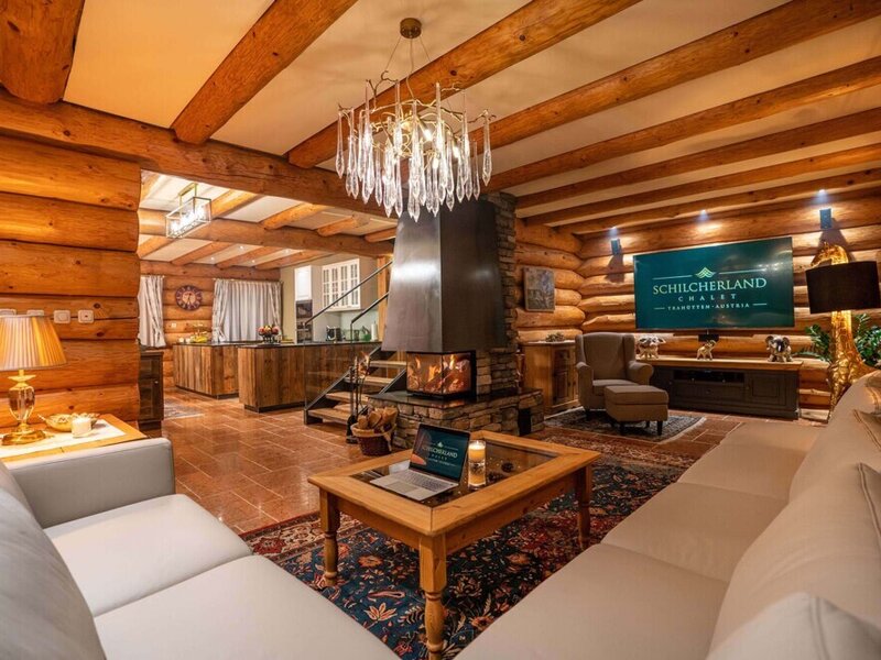 The cozy living area of the holiday home featuring rustic log walls, an inviting fireplace, and comfortable sofas.