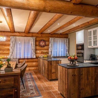 The holiday home's inviting kitchen and dining area with rustic log walls, modern appliances, and warm lighting.
