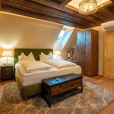 A cozy bedroom in the holiday home featuring a rustic wooden ceiling, a comfortable double bed, and warm, inviting lighting.