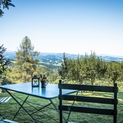 Outdoor seating with a table and chairs overlooking the hilly landscape from the farmhouse.
