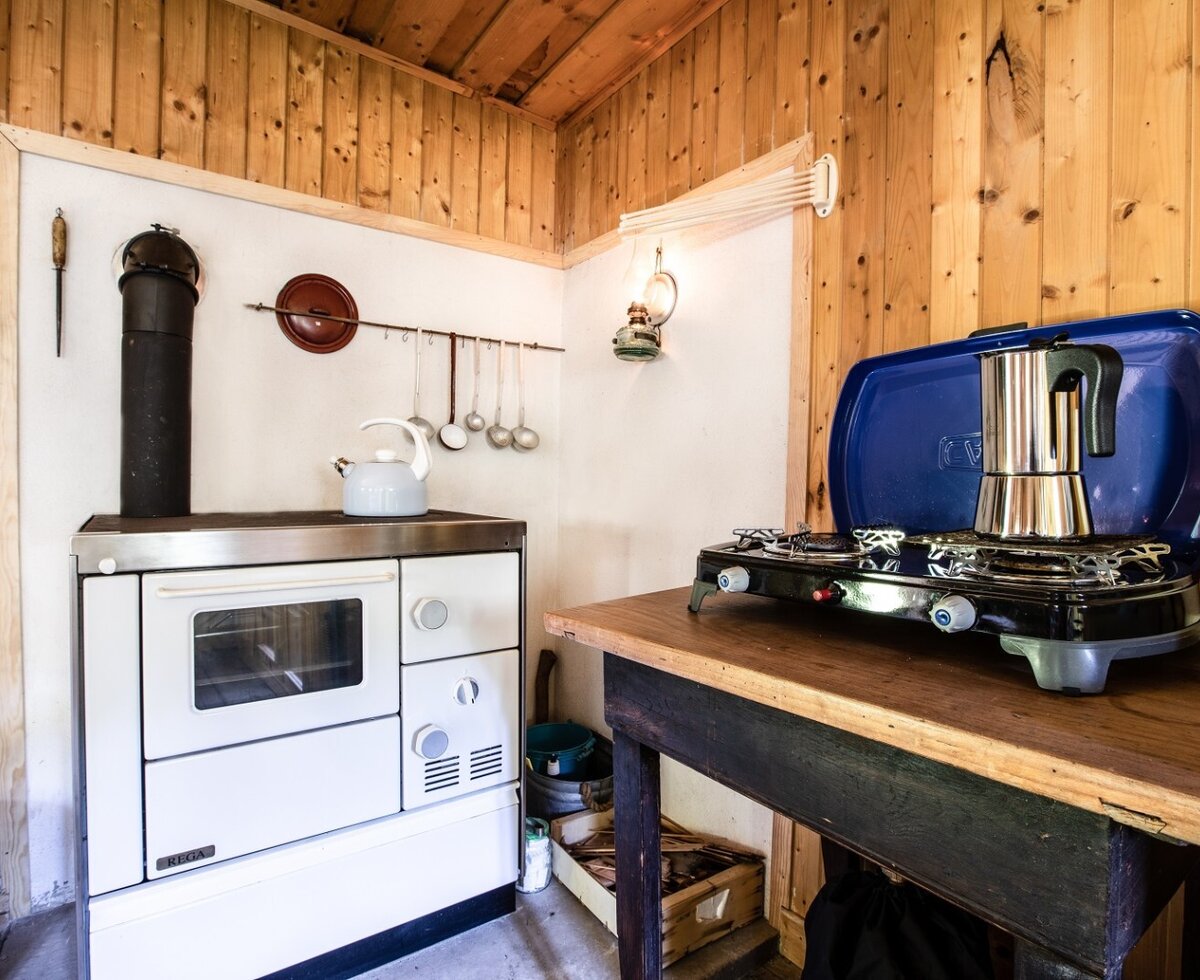 Cooking facilities in the farmhouse, featuring a traditional wood-burning stove and a portable gas stove.