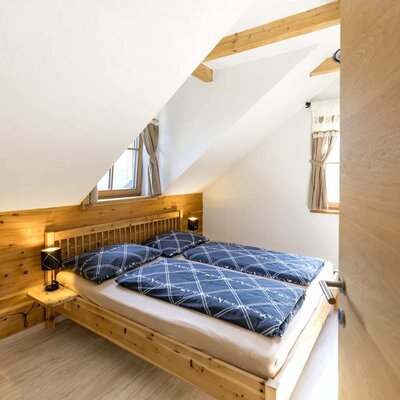 A cozy double bedroom in the farmhouse featuring rustic wooden furniture, charming sloped ceilings, and warm lighting.