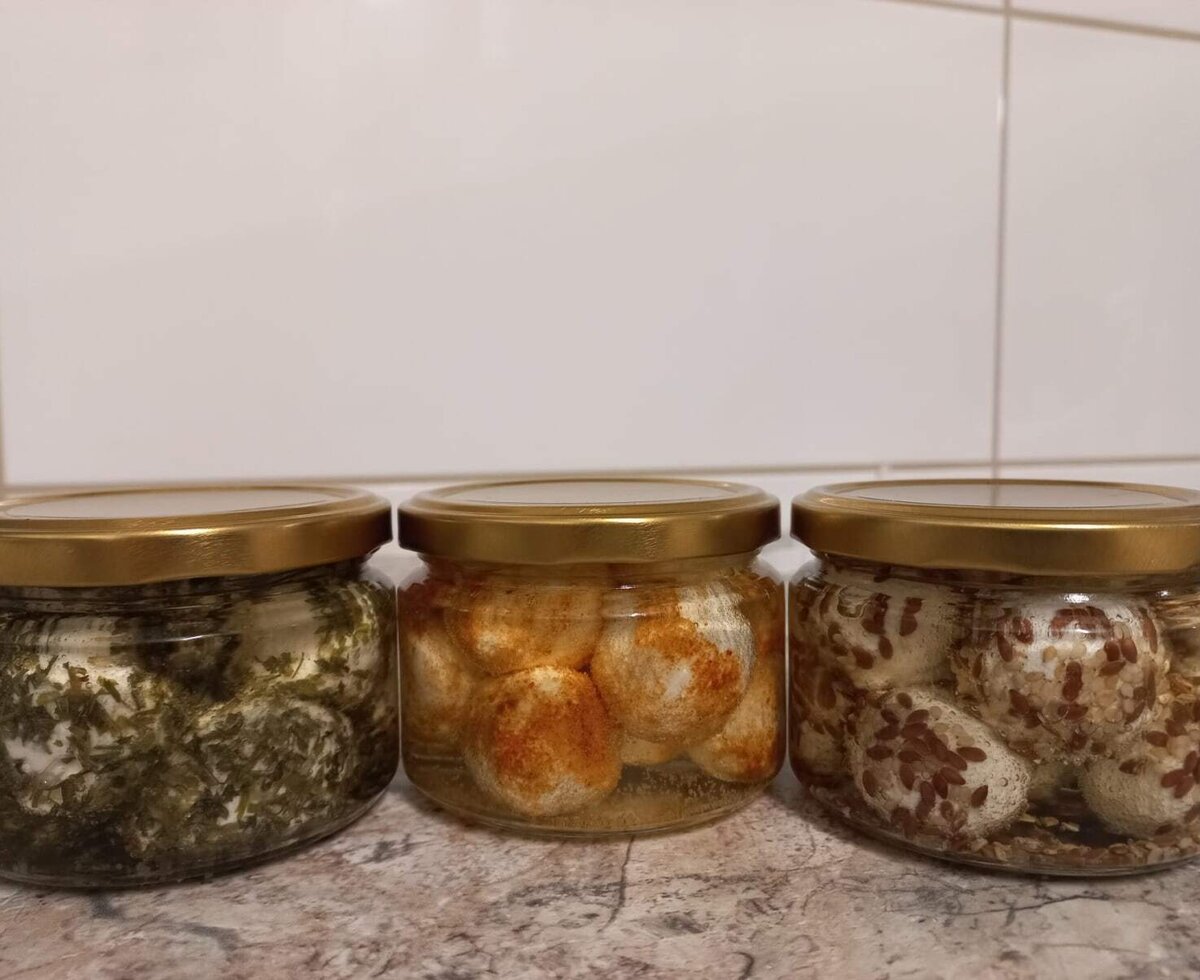 Homemade cheese specialties in jars from the farmhouse, appetizingly prepared with various herbs and spices.
