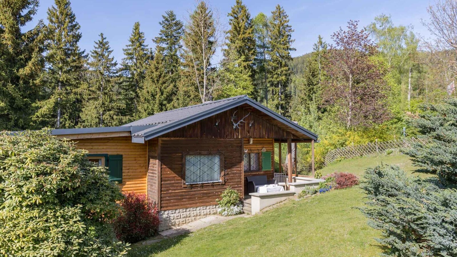 Exterior view of the Bed and Breakfast with a wooden facade, porch, and surrounding nature.