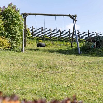 Wooden swing set with two swings, including a tire swing, on the lawn of the Bed and Breakfast.