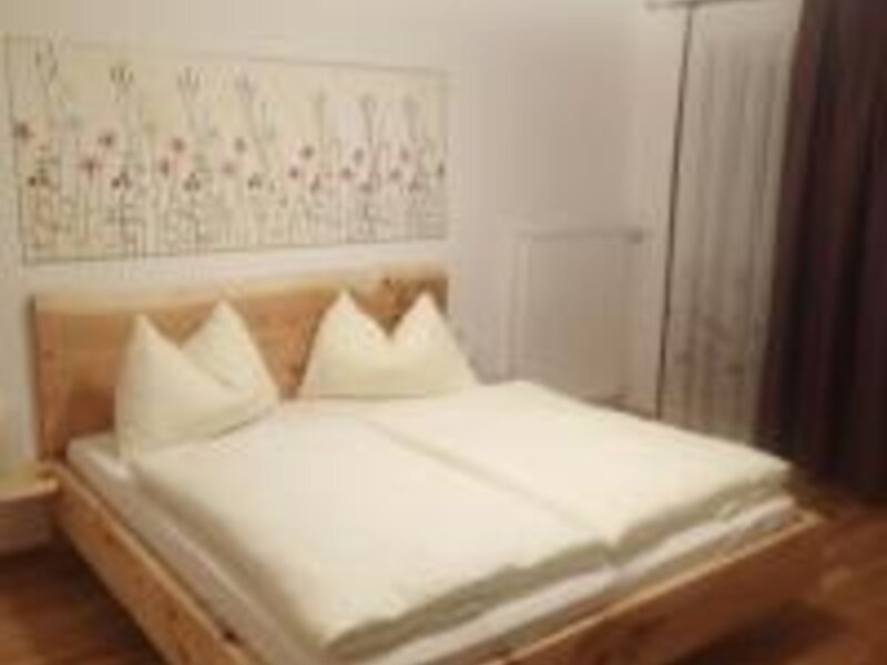 Double bedroom in the Farm House featuring a high-quality arolla pine bed with white bedding and a window.