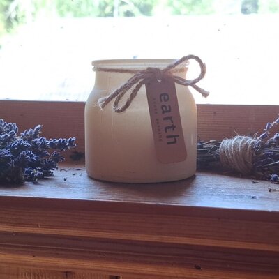 Charming decorations on a wooden windowsill of the farmhouse, featuring a scented candle and dried lavender.