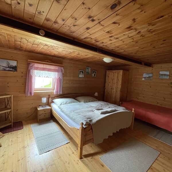 Three-bed room in the farmhouse, featuring a double bed, an additional single bed, and wooden interiors.