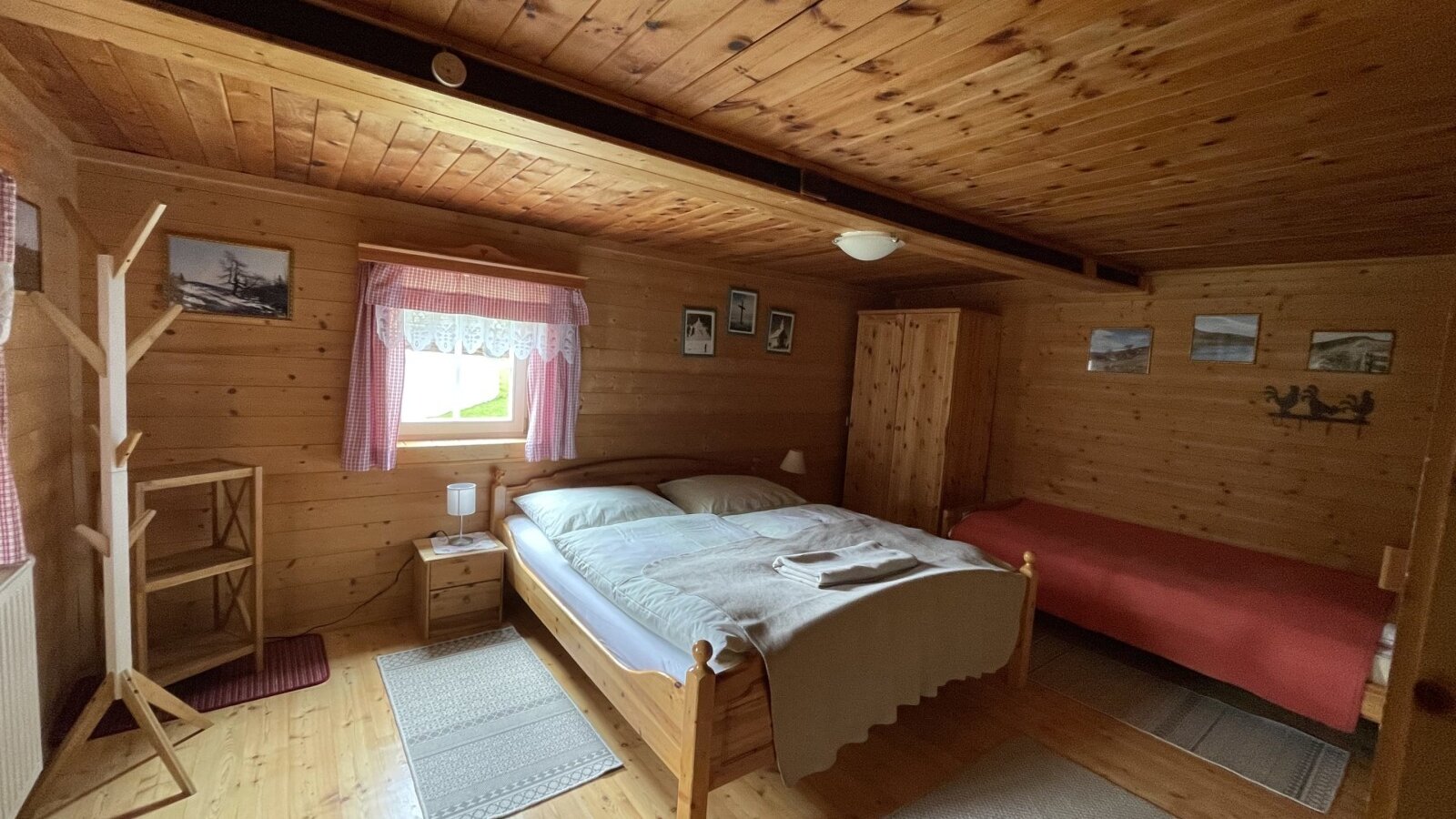 Three-bed room in the farmhouse, featuring a double bed, an additional single bed, and wooden interiors.
