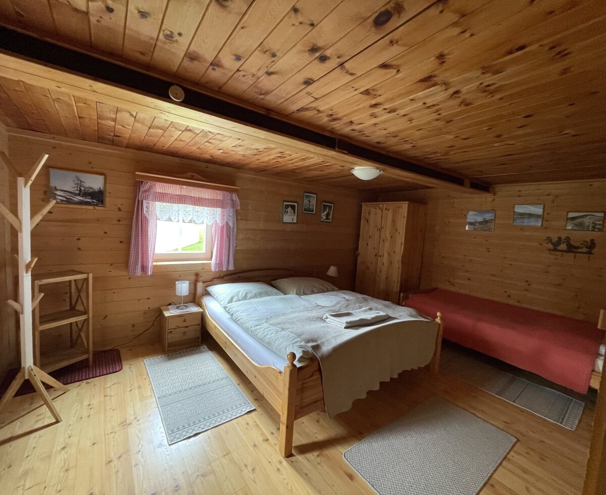 Three-bed room in the farmhouse, featuring a double bed, an additional single bed, and wooden interiors.