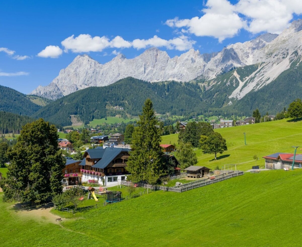 The farmhouse offering views of the mountain landscape, surrounded by green meadows.