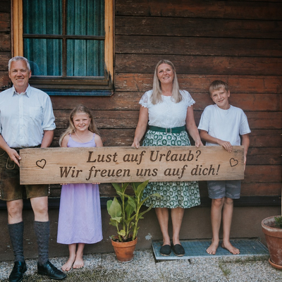 The host family of the Troadkasten holding a welcome sign in front of the building.