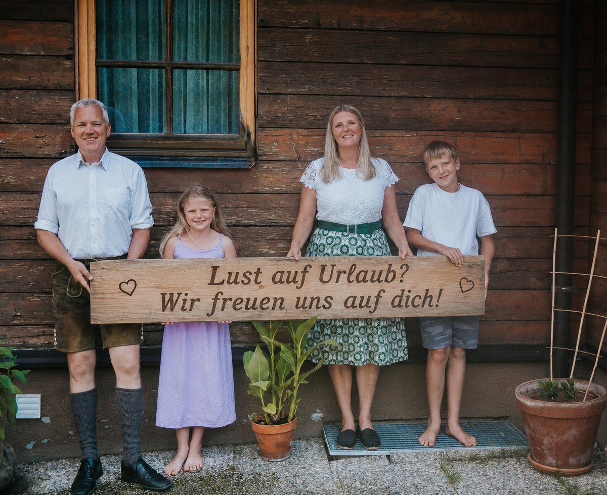 The host family of the Troadkasten holding a welcome sign in front of the building.