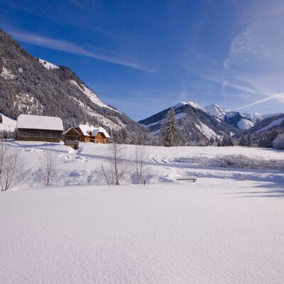 Winter landscape featuring snow-covered mountains and traditional wooden buildings at the Schaffergut.