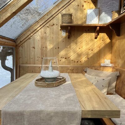 The apartment's winter garden featuring a dining table, bench seating.