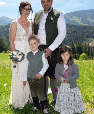A wedding couple with their children in a mountain meadow near the Bed and Breakfast.