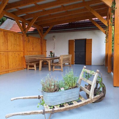 Covered outdoor dining area at the Farm House, furnished with a wooden table and benches.