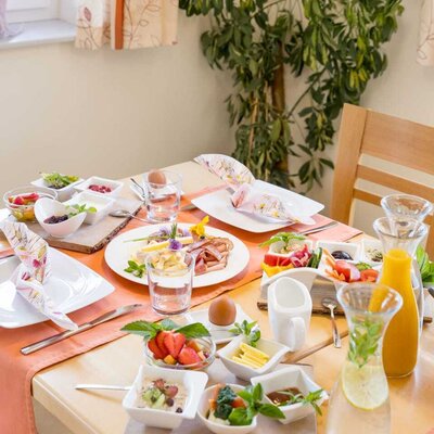 Breakfast table with cold cuts, cheese, eggs, fruit, muesli, and drinks at the farmhouse. (c) Elisabeth Fröhlich Photography