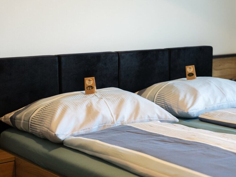 Bedroom in the Haus with a double bed, dark headboard, striped bedding, and small tags on the pillows.