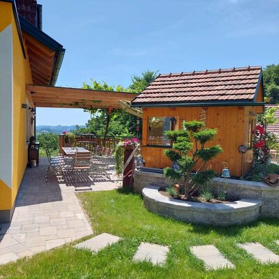 Terrace of the Haus with seating under a pergola, surrounded by a garden with distant views.