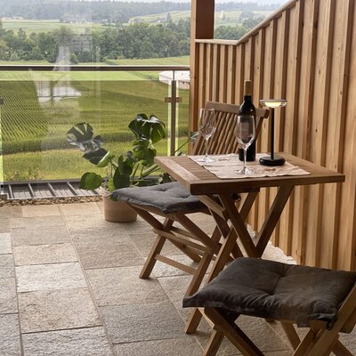 Balcony at the farmhouse with a table and two chairs, offering views of the surrounding fields.