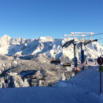 Ski area with a chairlift and snow-covered mountains.