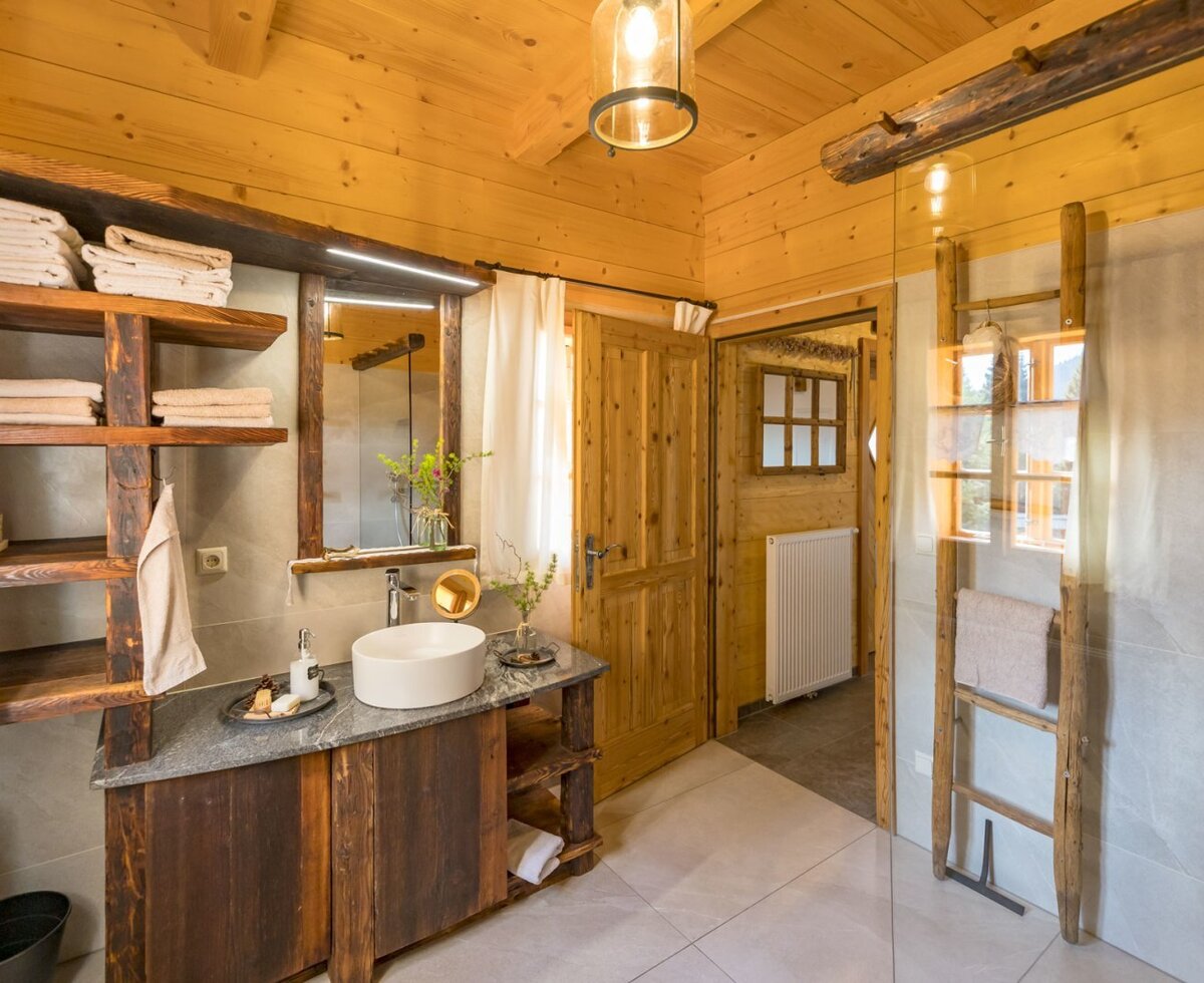 Bathroom in the Bed and Breakfast with wooden walls, a wooden and stone vanity, an illuminated mirror, and a glass shower partition.